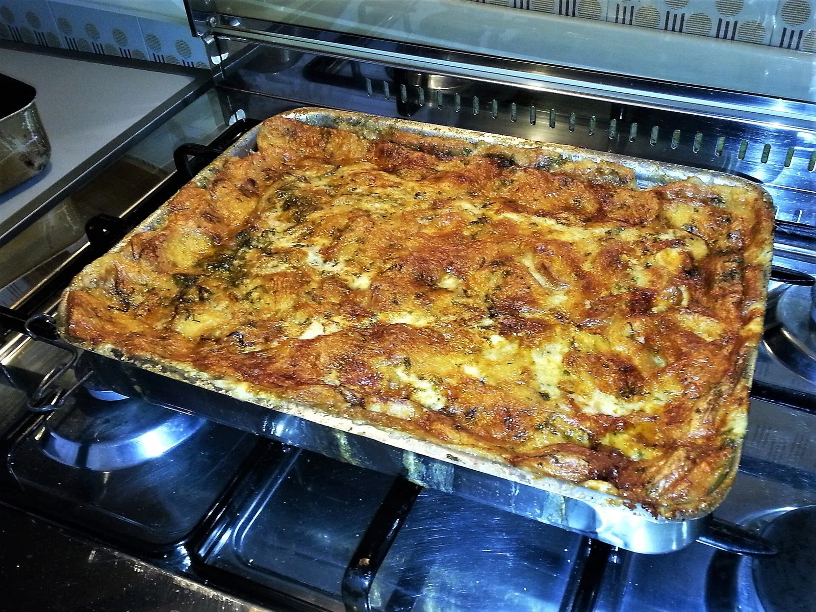 Teglia di zuppa gallurese appena sfornata, con la superficie di formaggio dorata e croccante