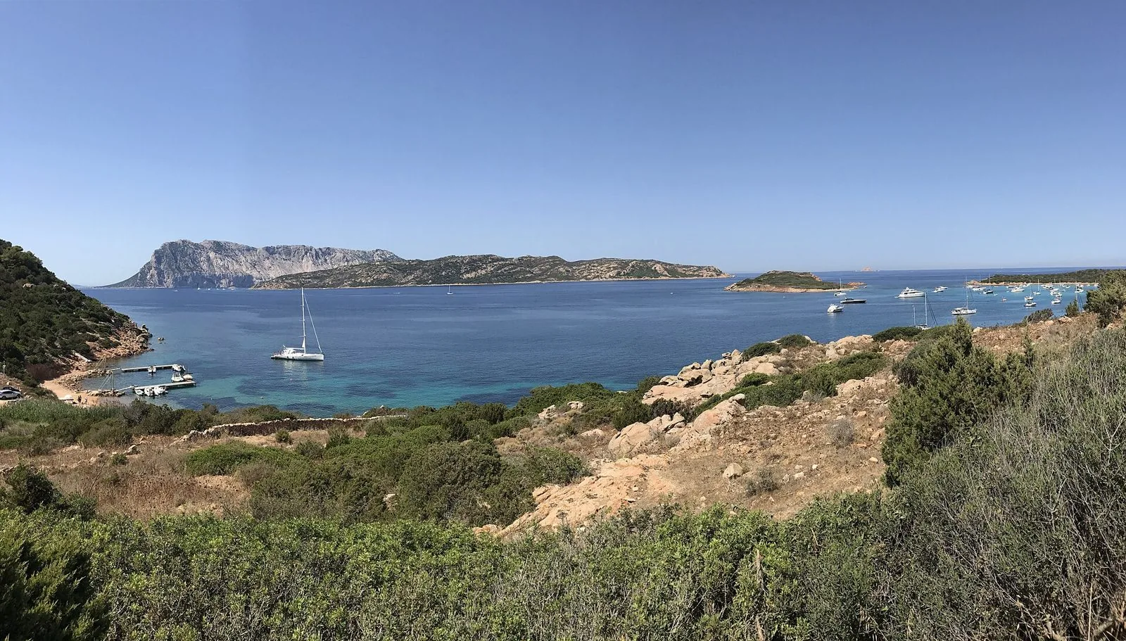 Panorama da Capo Coda Cavallo sulla baia con barche a vela, l'isola di Tavolara e l'isola di Molara sullo sfondo